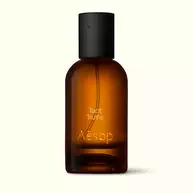 Amber glass Aesop Tacit Truths Eau de Parfum bottle with black cap on a white background.