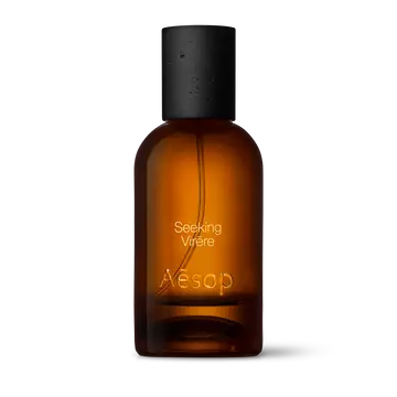 Amber glass Aesop Seeking Virere Eau de Parfum bottle with black cap on a white background.