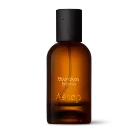 Amber glass Aesop Boundless Eremia Eau de Parfum bottle with black cap on a white background.