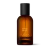 Amber glass Aesop Entirely Aurner Eau de Parfum bottle with black cap on a white background.