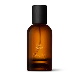 Amber glass Aesop Rozu Arises Eau de Parfum bottle with black cap on a white background.